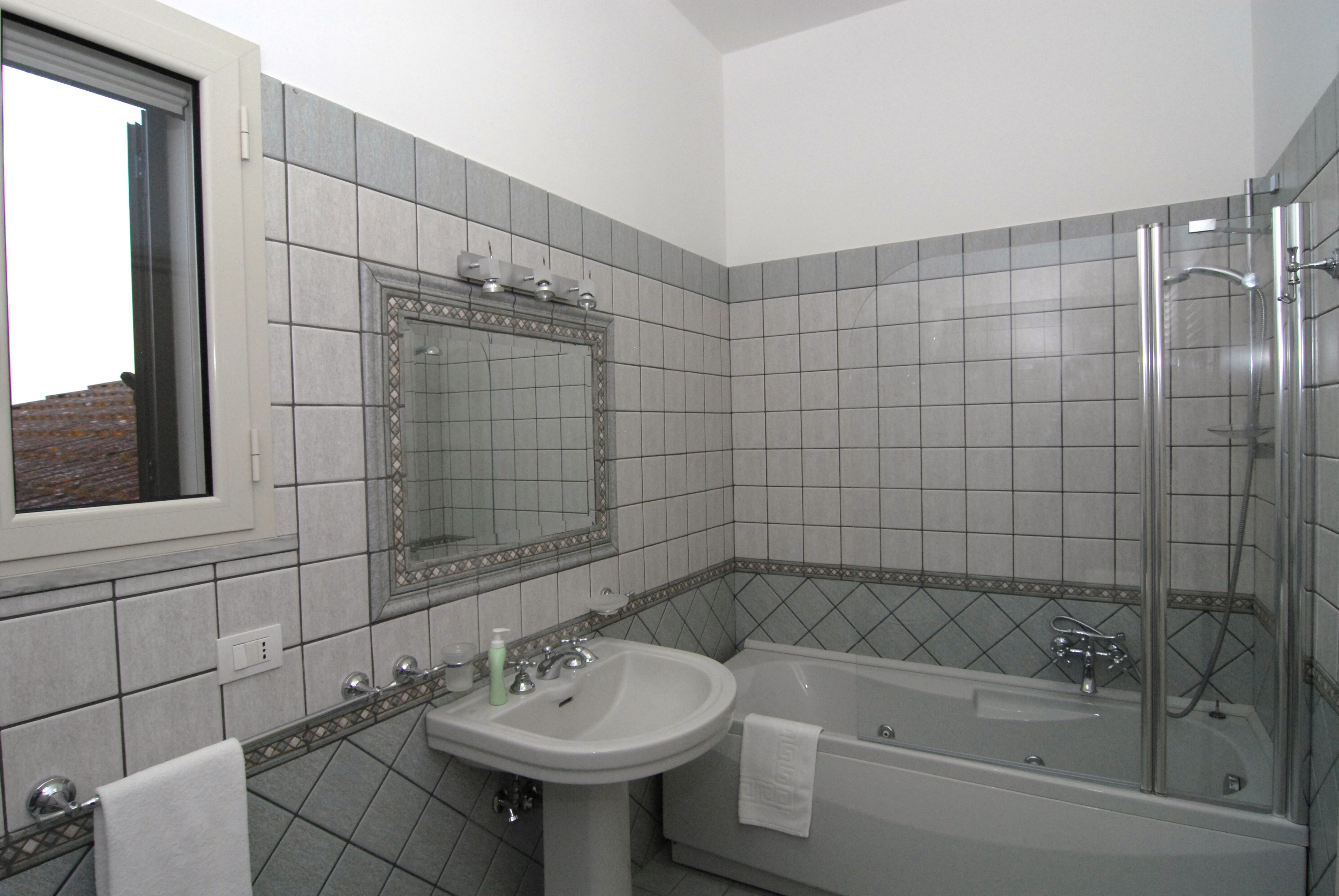 A bathroom with a sink, mirror, and bathtub.