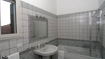 A bathroom with a sink, mirror, and bathtub.