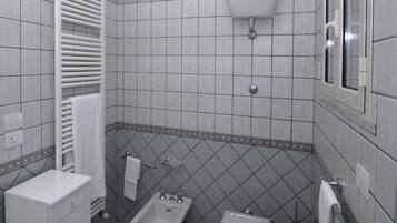 Une salle de bain équipée d’un bidet, de toilettes, d’un porte-serviettes et d’un meuble blanc.