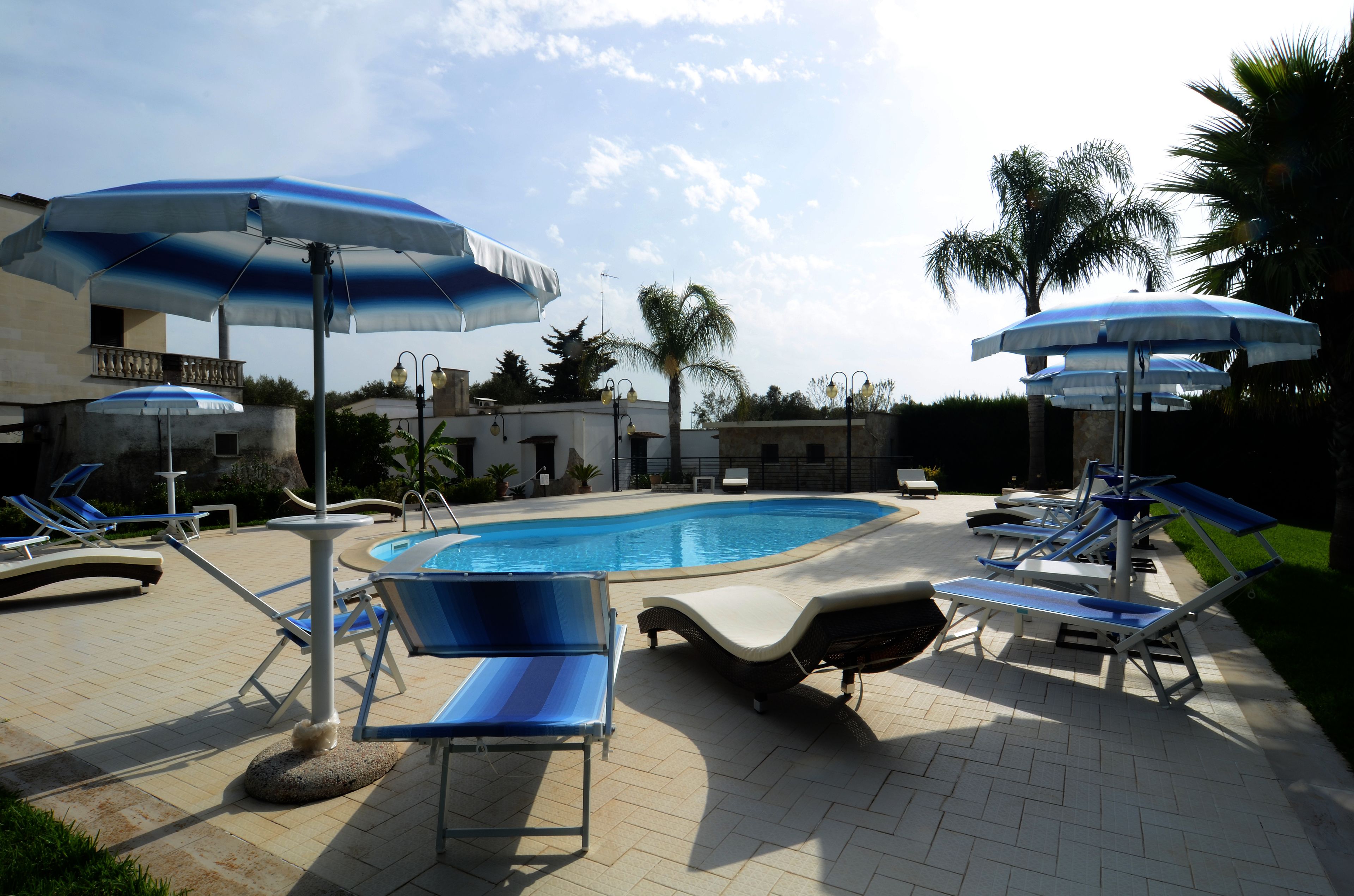 Un área de piscina con sillones de descanso y sombrillas.