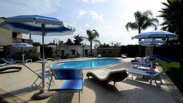 Un área de piscina con sillones de descanso y sombrillas.