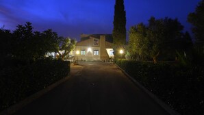 Un edificio con una torre central destacada, una entrada bien iluminada y un camino de entrada pavimentado.