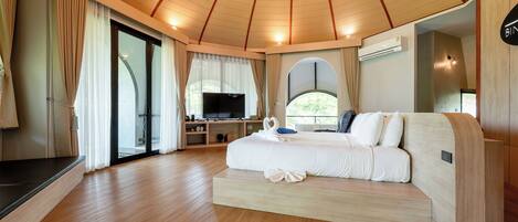 A spacious room with a large bed, a television, and a sliding glass door leading to a balcony.