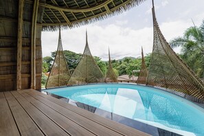 A pool with a wooden deck and thatched roof overhead. - Binlha Raft Resort (Sai Yok)