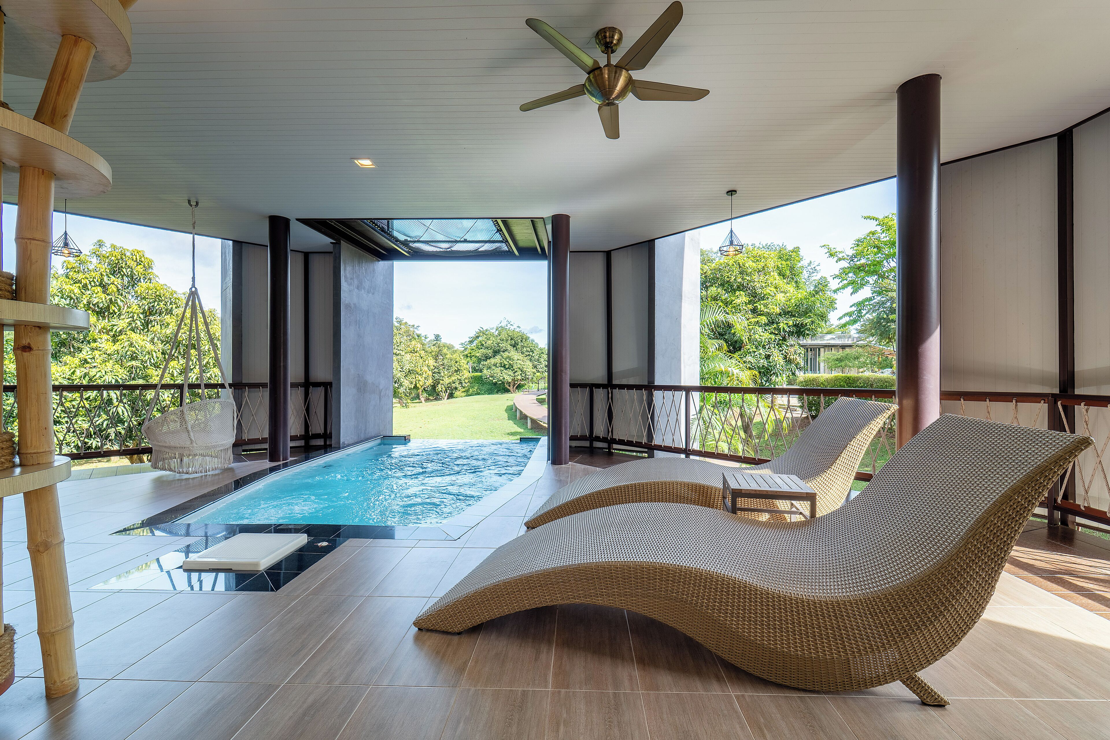 Uma área moderna de piscina ao ar livre com espreguiçadeiras e um ventilador de teto.