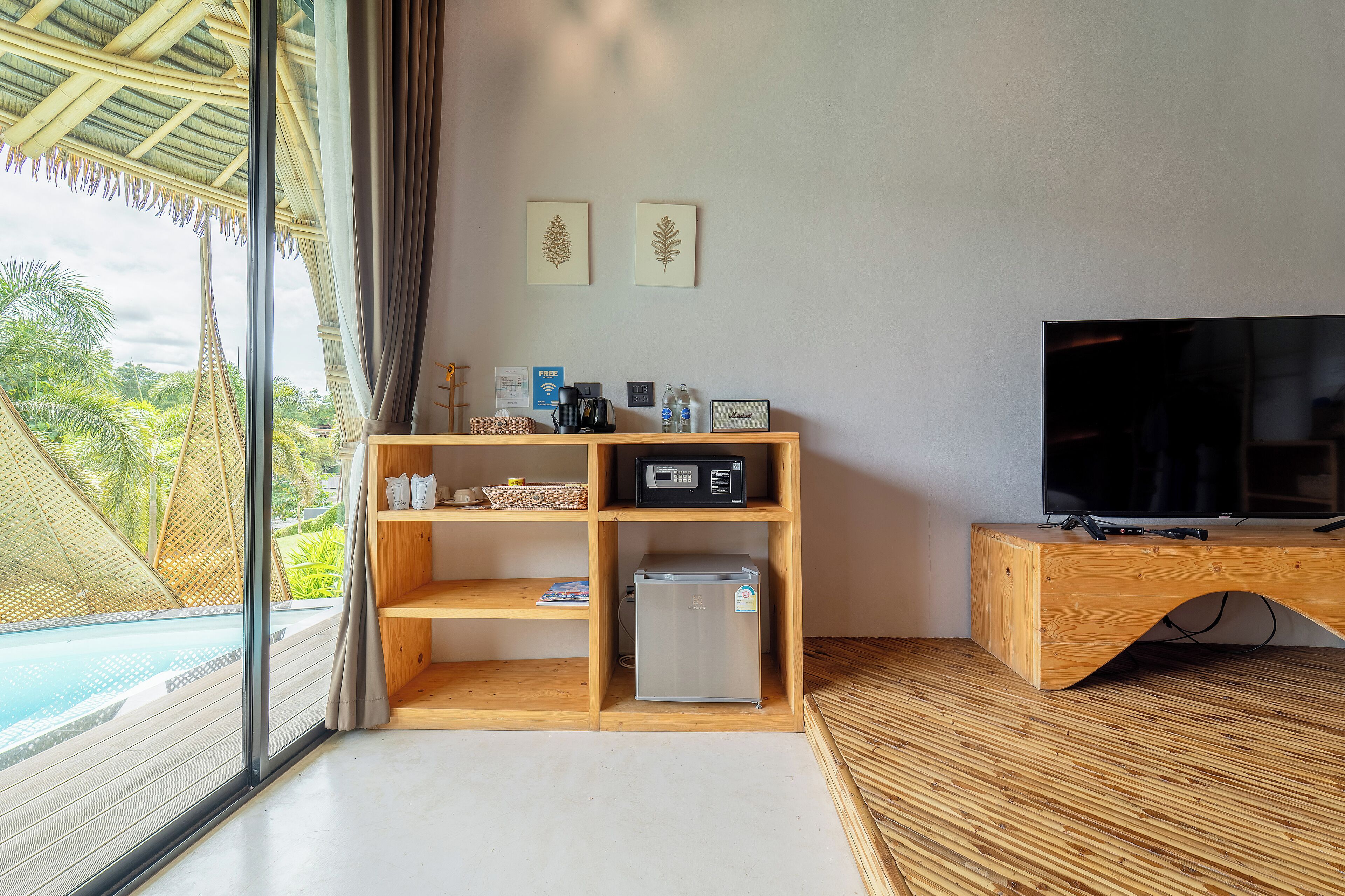 A modern room with a wooden TV stand, a refrigerator, and a shelf with various items.