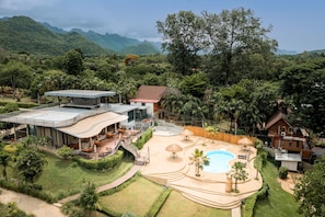 Un complejo turístico con piscina, asientos al aire libre y vistas del bosque circundante.