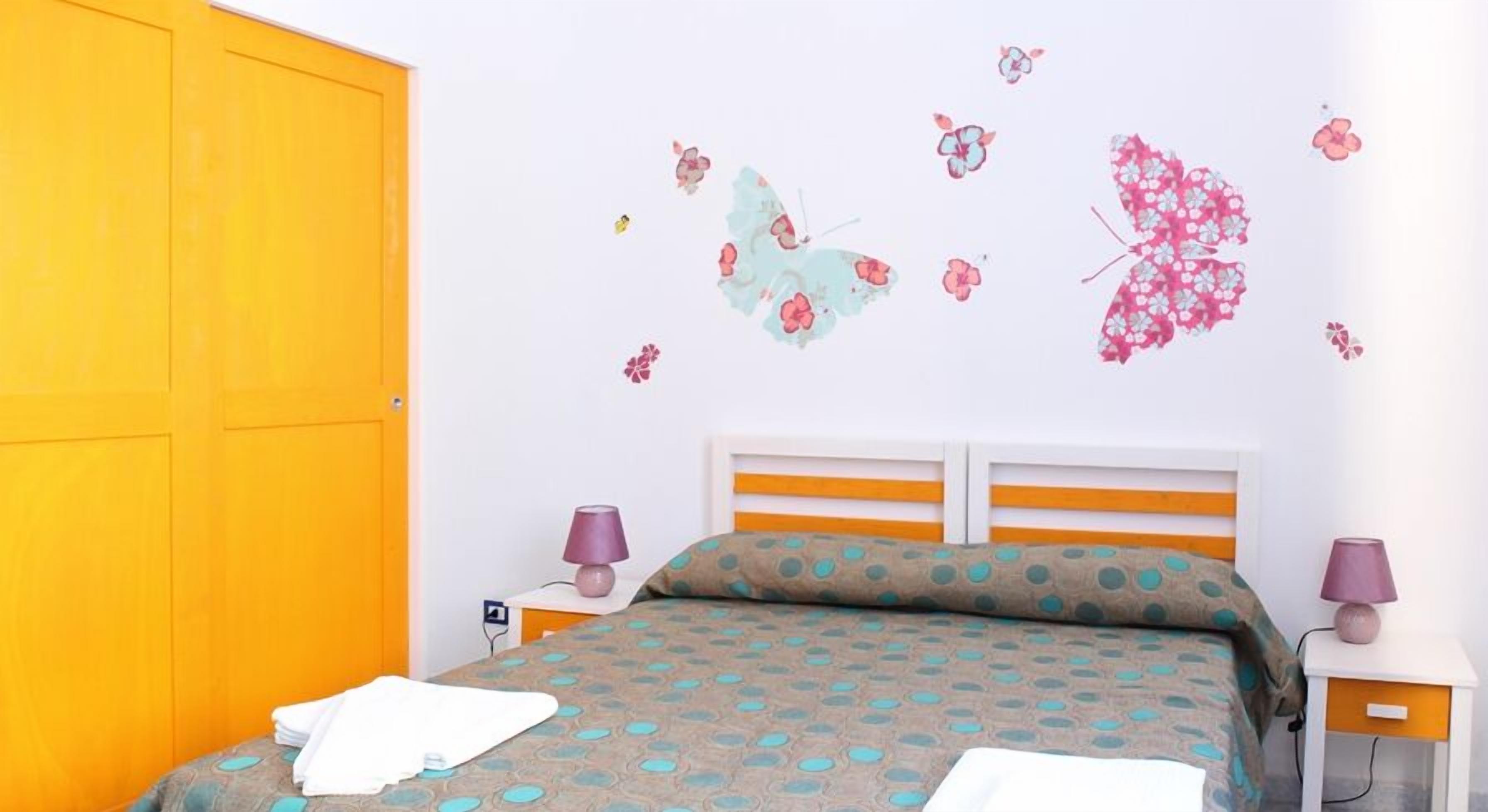 A bedroom with a bed, two nightstands, a lamp, and a wardrobe.