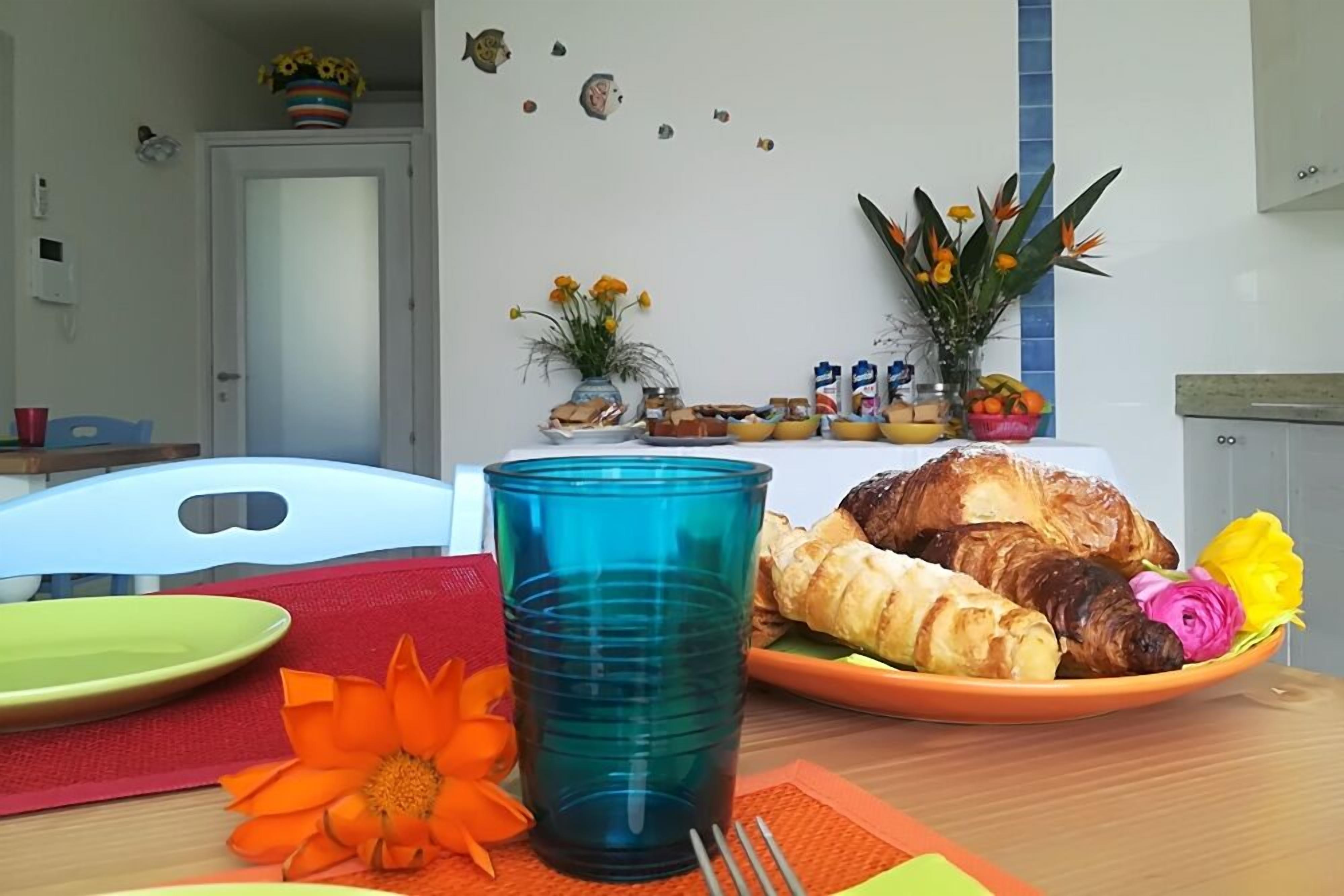 A dining table with plates, a blue glass, and food items.