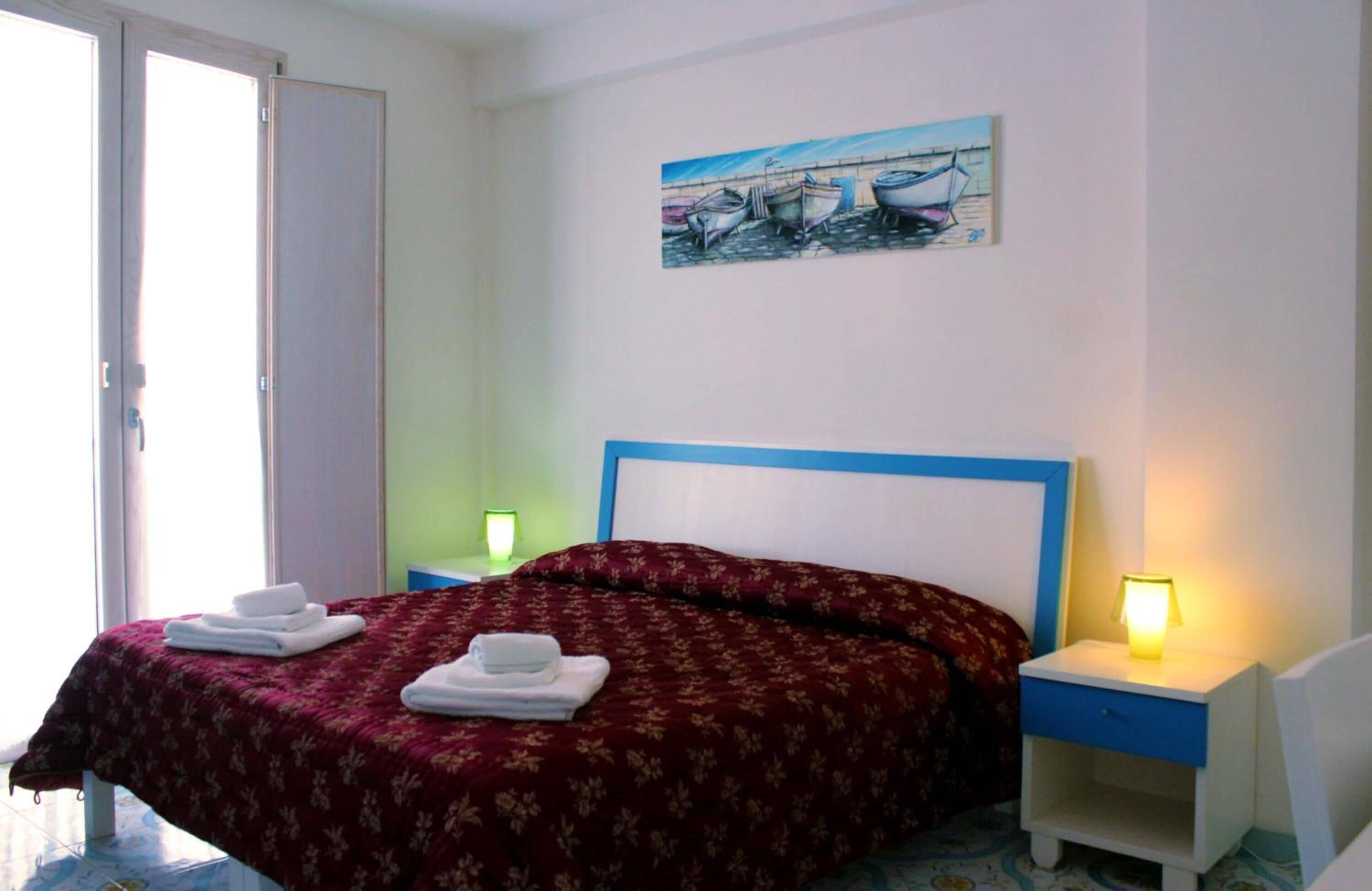 Une chambre à coucher avec un lit, deux tables de chevet, un tableau et une porte.