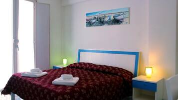 Une chambre à coucher avec un lit, deux tables de chevet, un tableau et une porte.