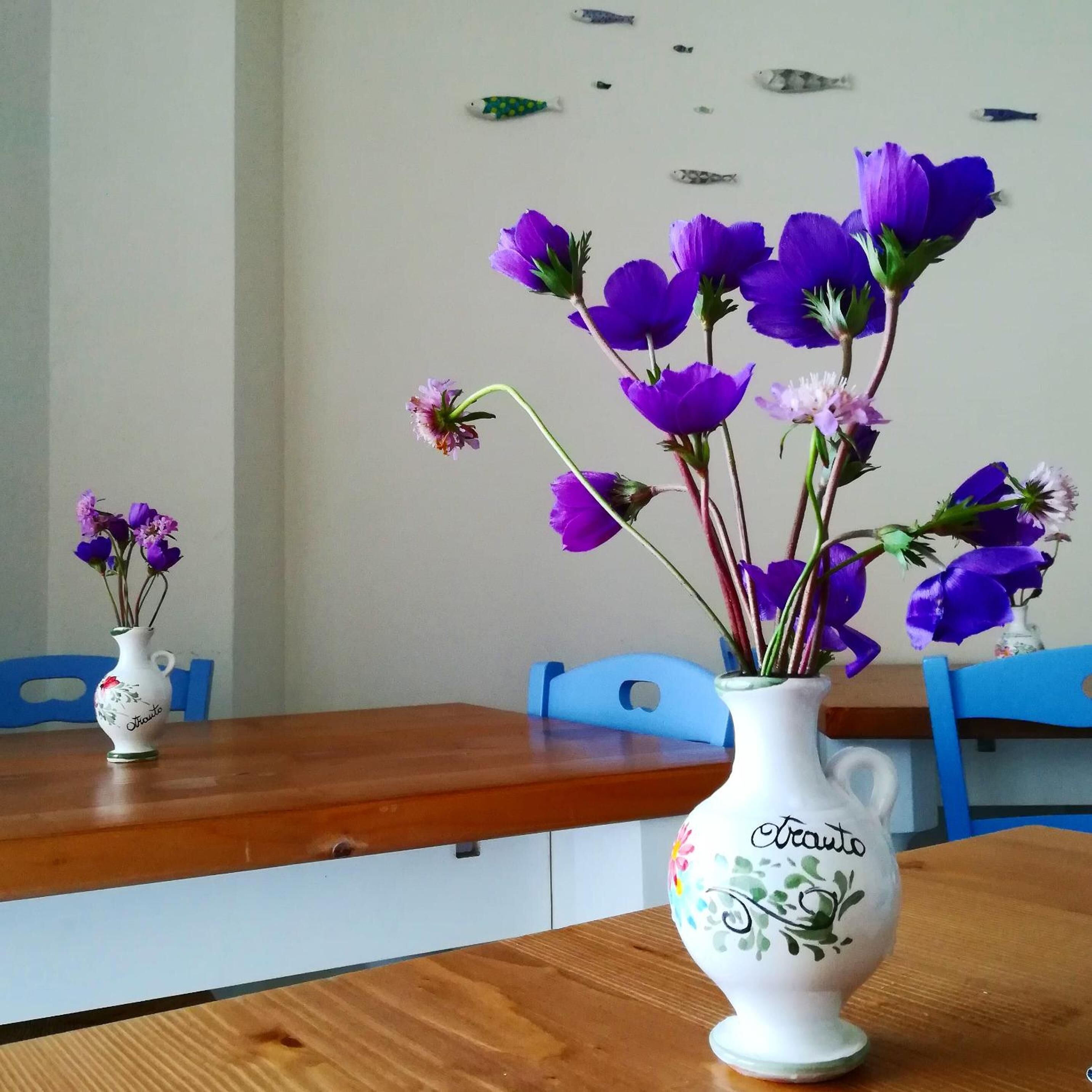 Two white vases with floral designs on a wooden table.