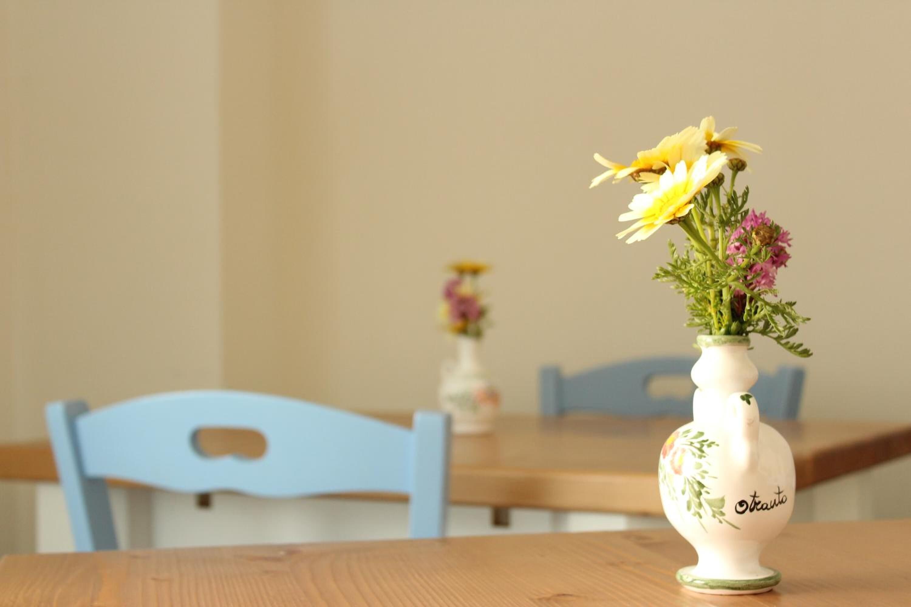 A white vase with floral designs on a wooden table.