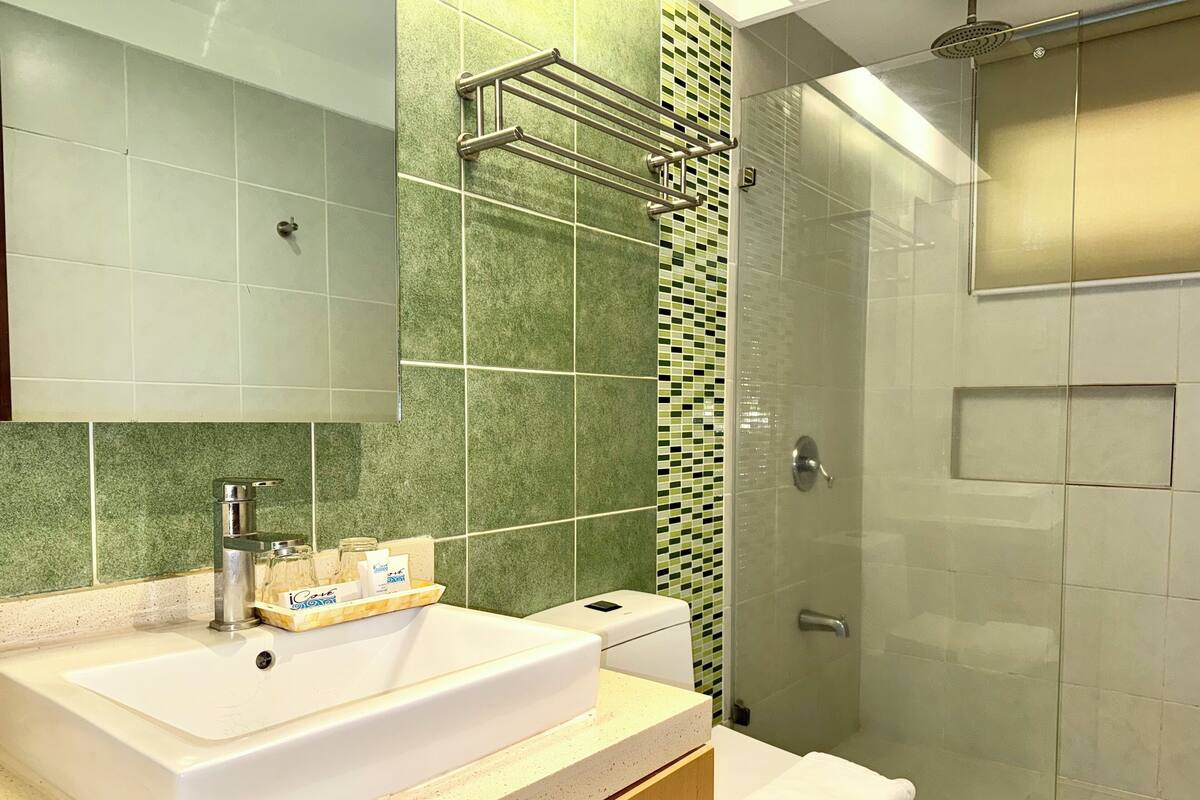 A bathroom with a white sink, a mirror, a shower with a glass door, and a toilet.