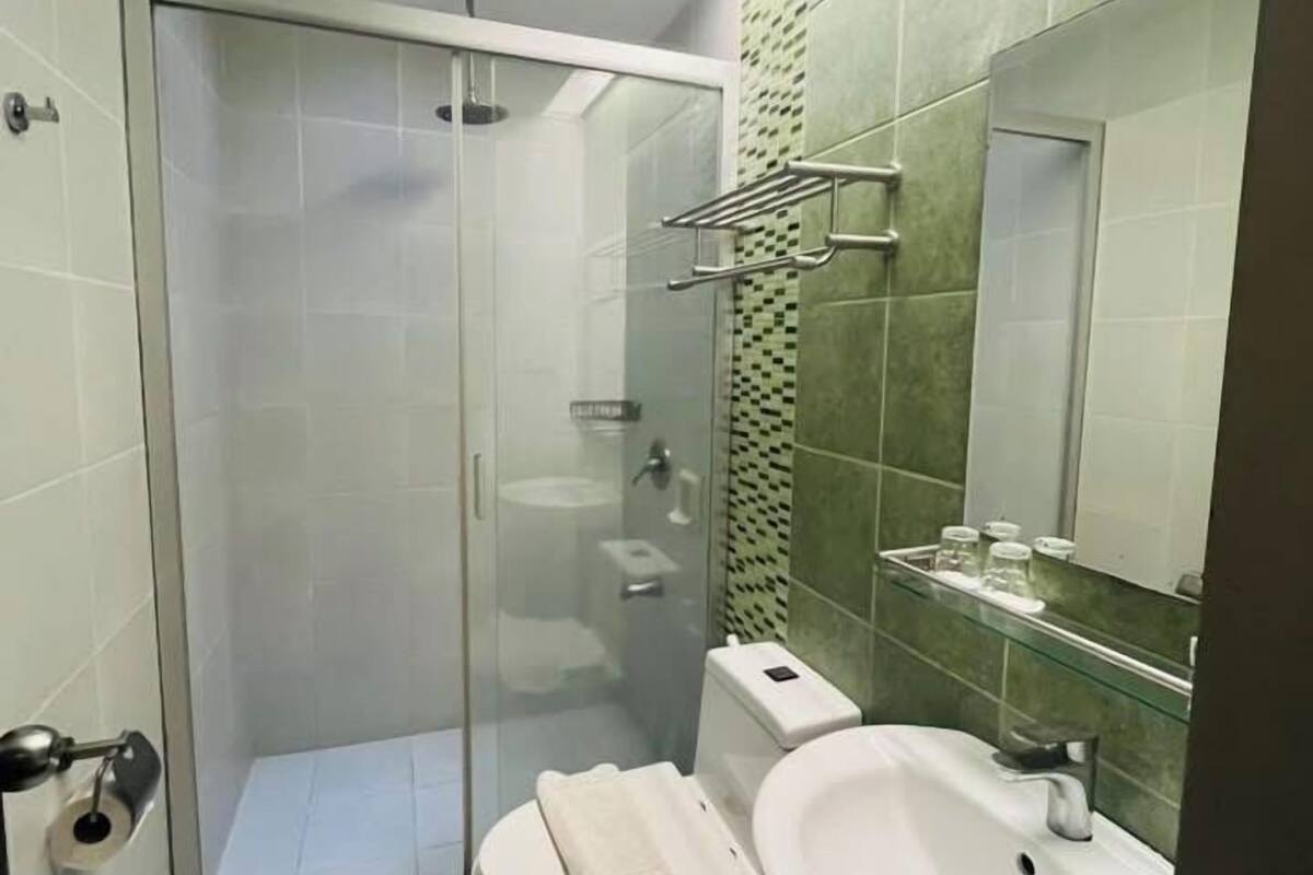 A modern bathroom with a glass-enclosed shower, a toilet, and a sink with a mirror above it.