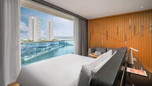 Habitación de hotel con una cama grande, una mesita, una silla y vistas a la ciudad y al río.