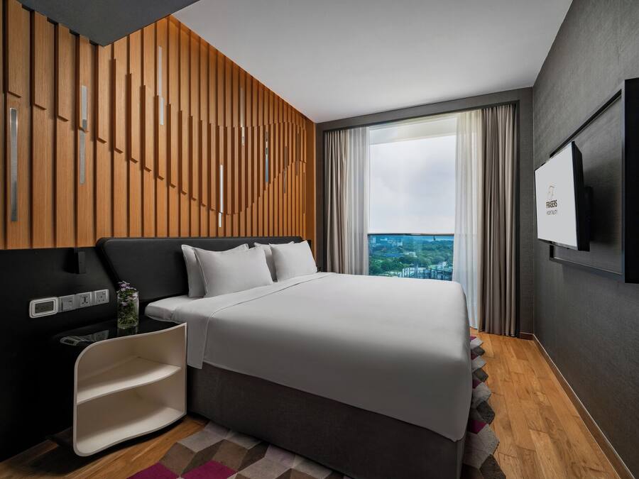 Ein modernes Hotelzimmer mit einem großen Bett, einem an der Wand montierten Fernseher und Blick auf die Stadt.