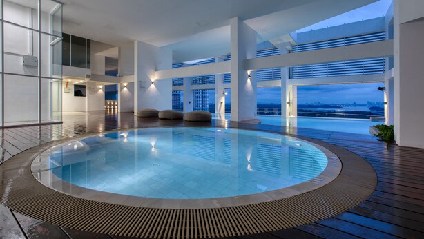 Una piscina interior moderna con vistas a la ciudad al atardecer.