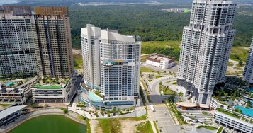 A high-rise residential building with multiple balconies, a swimming pool, and a landscaped area with pathways and greenery.