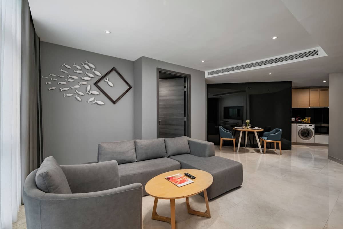 A modern living room with a grey sofa, a wooden coffee table, and a dining area with chairs and a table.