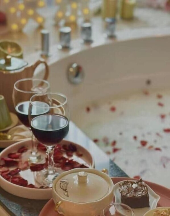 A table set with a teapot, two wine glasses, a dessert, and scattered rose petals. - Fraser Place Puteri Harbour (Iskandar Puteri)