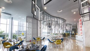 Un restaurante moderno con techos altos, muebles contemporáneos y vistas a la ciudad.