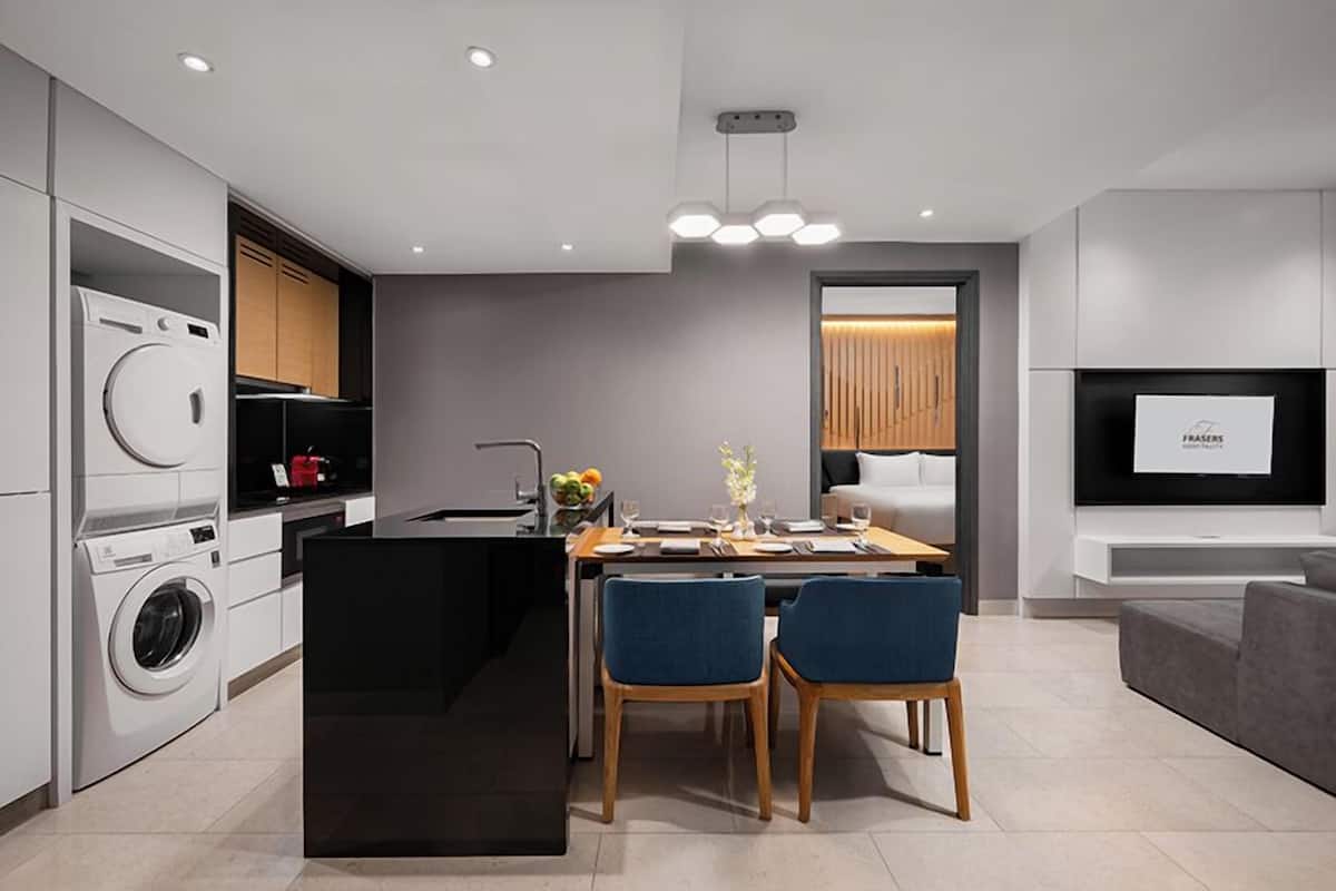 A modern kitchen with a central island, built-in appliances, and a dining area with two chairs.