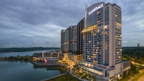 Un hotel moderno de gran altura, con varios pisos, un letrero llamativo y vistas al agua.