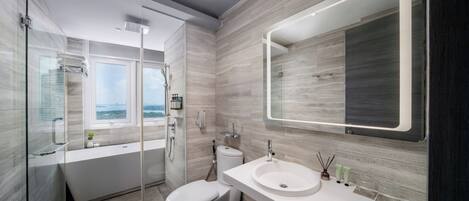 A modern bathroom with a glass-enclosed shower, a white toilet, a large sink, and a mirror with integrated lighting.