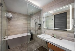 A modern bathroom with a glass-enclosed shower, a freestanding bathtub, and a vanity with a large mirror.