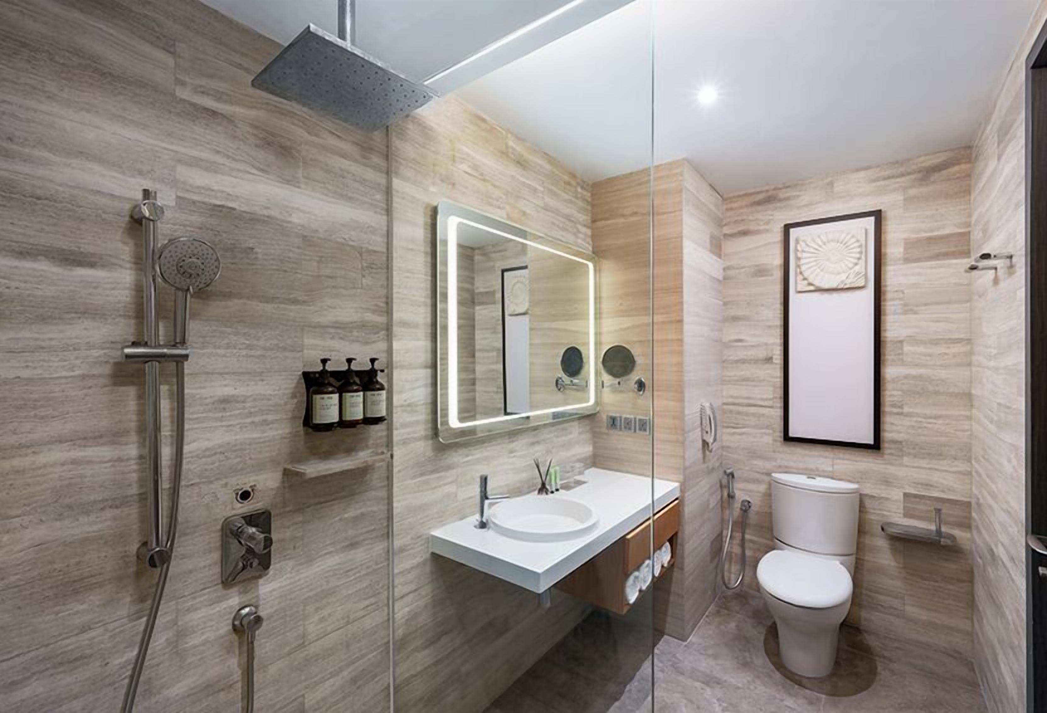 A modern bathroom with a glass-enclosed shower, a white sink, and a toilet.