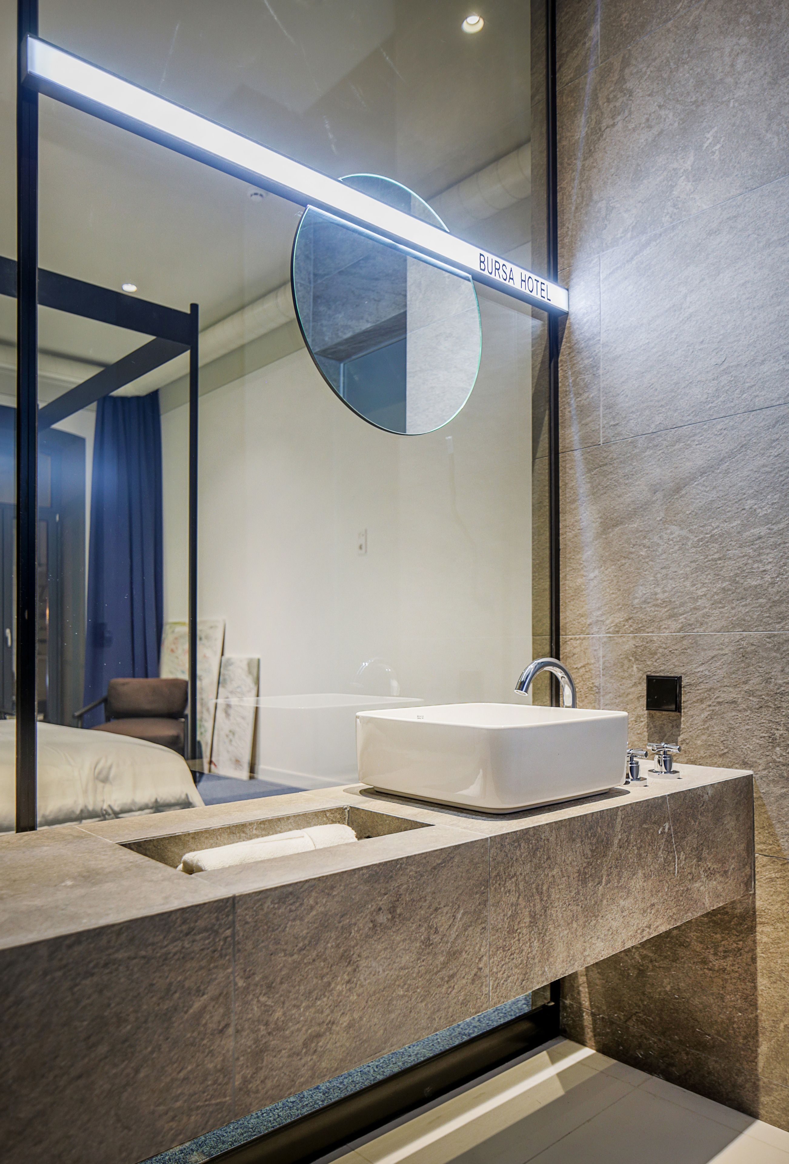 A modern bathroom with a large mirror, a white sink, and a bathtub.