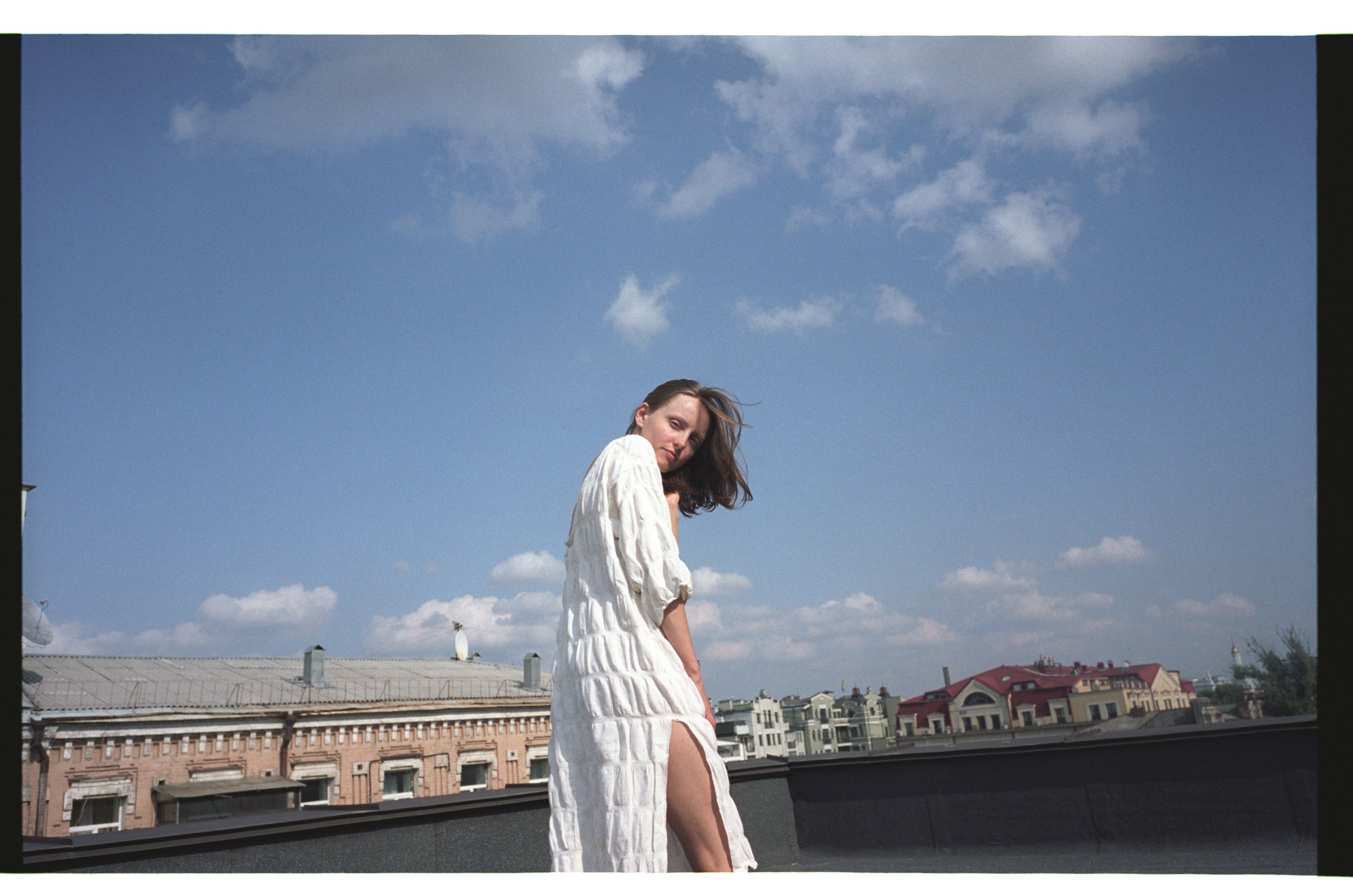 A person standing on a rooftop with a clear sky and buildings in the background.