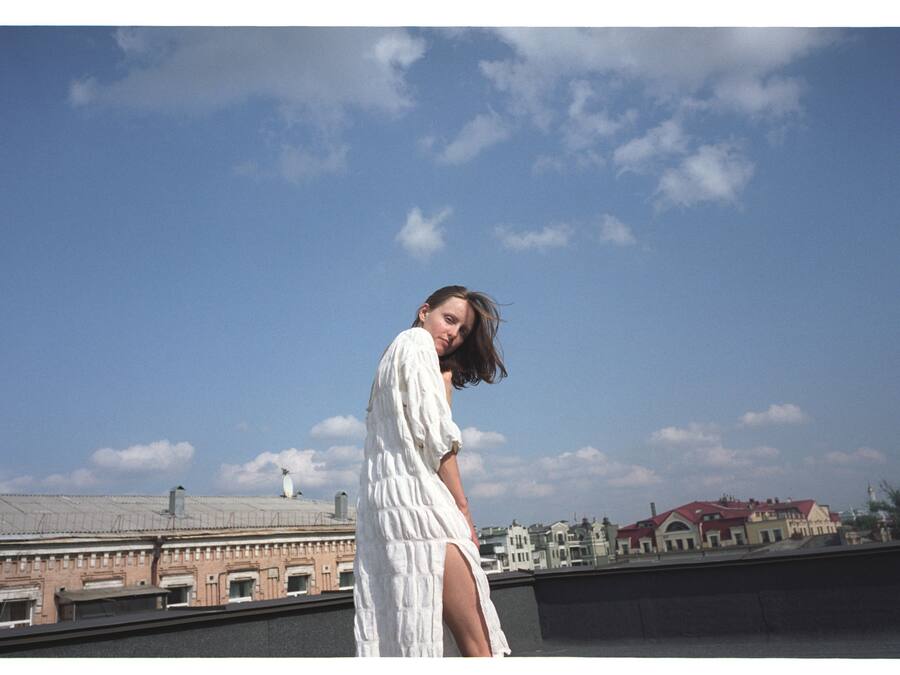 A person standing on a rooftop with a clear sky and buildings in the background.