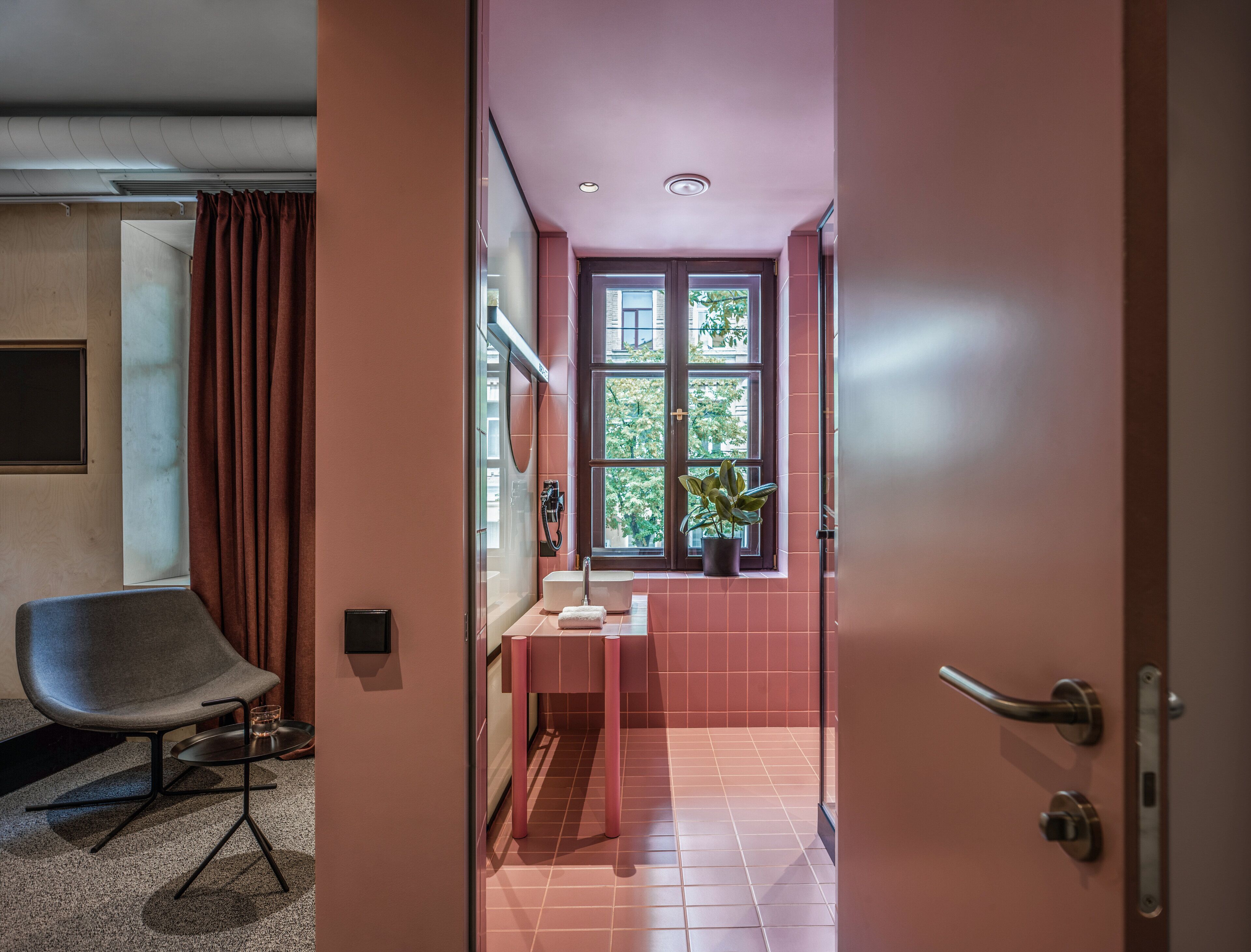 Un baño moderno con ducha, lavamanos y ventana con vistas a árboles.