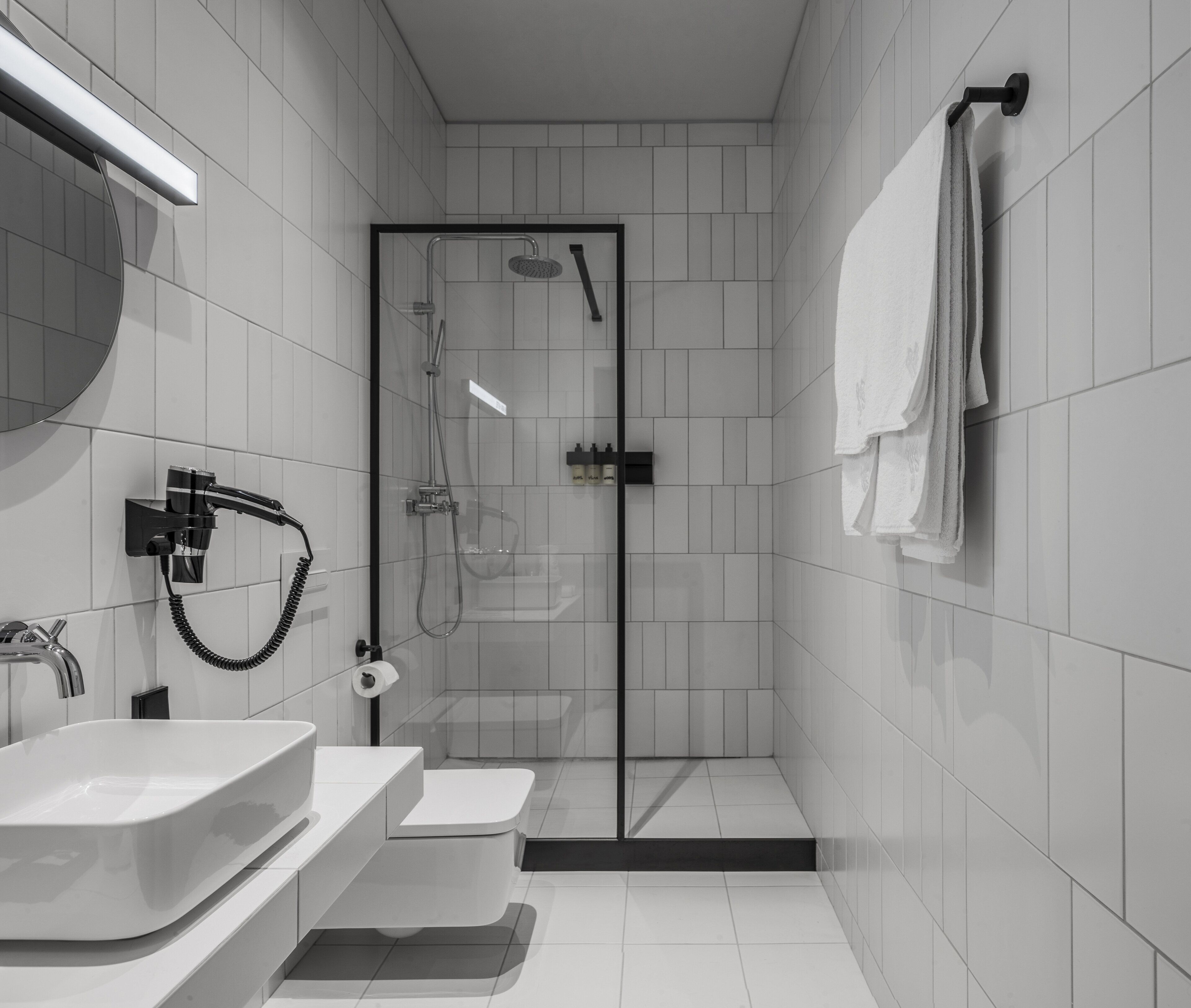 A modern bathroom with a glass-enclosed shower, a white sink, and a toilet.