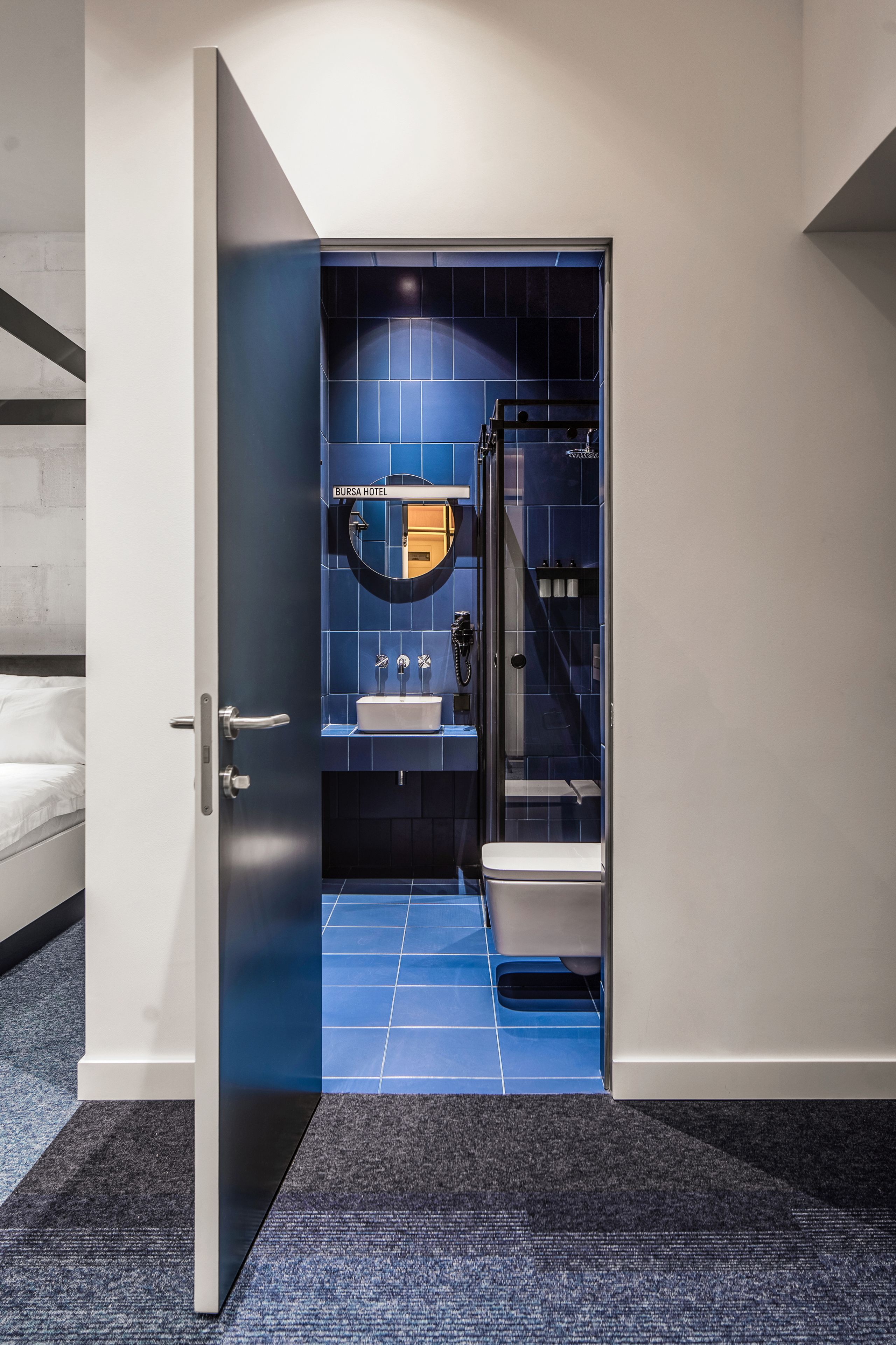 Un baño moderno con pared de azulejos azules, un lavabo y un inodoro.