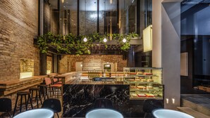 A modern bar area with a marble counter, seating, and a glass display case with desserts. - BURSA Hotel Kyiv (Kyiv)