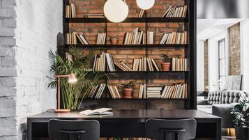 A modern dining area with a brick wall bookshelf, two black chairs, and a round pendant light.