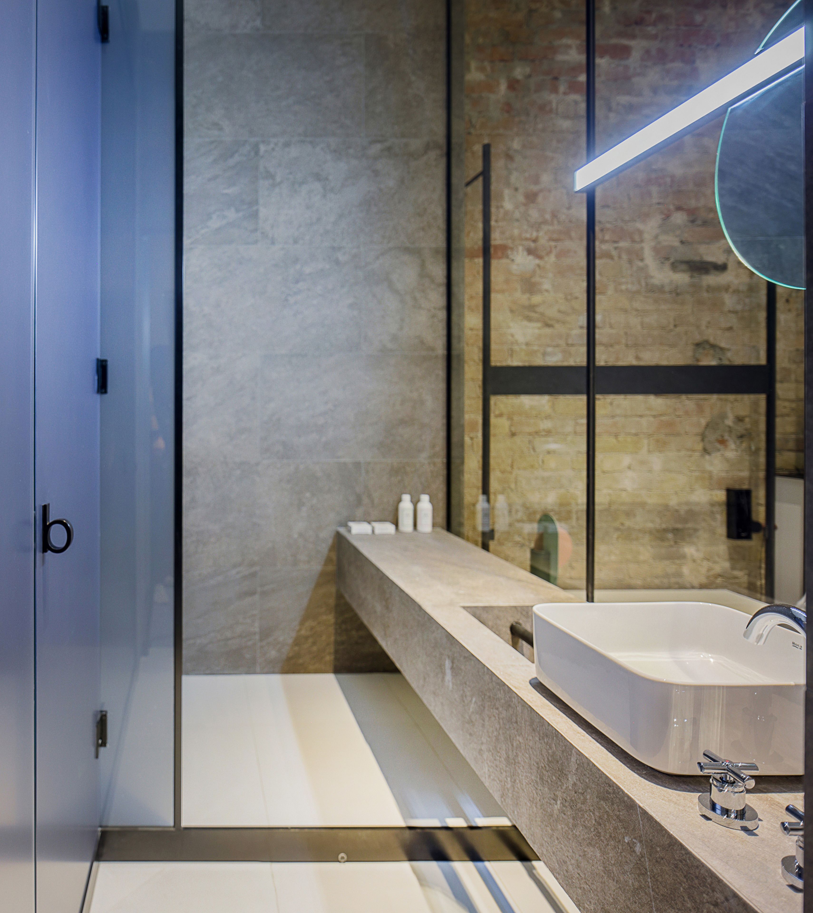 Een moderne badkamer met een grote spiegel, een witte wastafel en een douchecabine van glas.