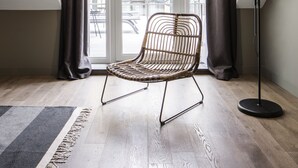 A room with a sloped ceiling, a wicker chair, a floor lamp, and a view through a window with curtains. - BURSA Hotel Kyiv (Kyiv)