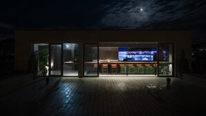 A modern building with a bar area, large windows, and a wooden deck. - BURSA Hotel Kyiv (Kyiv)