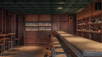 A bar area with wooden paneling, a long counter, and multiple stools.