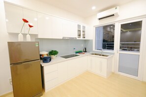 Una cocina moderna con armarios blancos, un refrigerador de acero inoxidable, un lavamanos y una ventana con vistas.