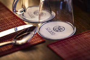 Una mesa servida con una copa, una cuchara y un cuchillo sobre un mantel texturizado.