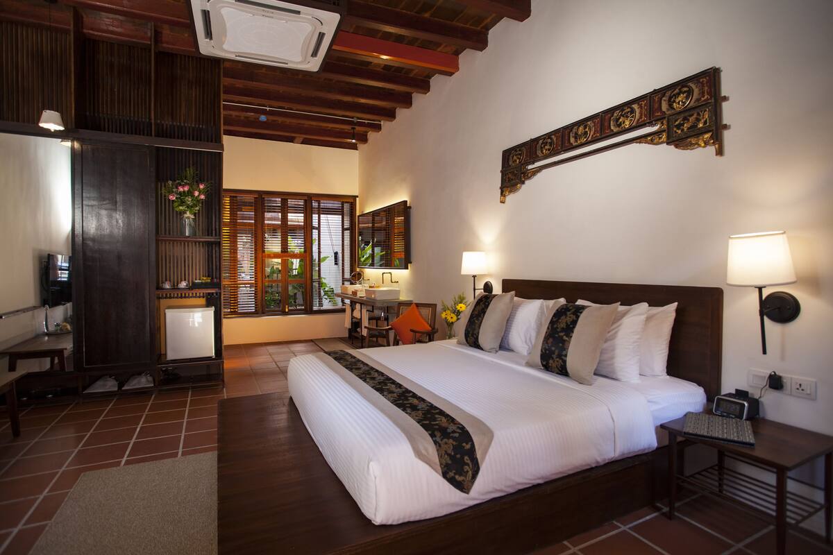 Une chambre d’hôtel avec un grand lit, des tables de chevet, un bureau et une vue sur l’extérieur par une fenêtre.