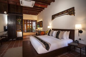 Una habitación de hotel con una cama grande, mesitas de noche, un escritorio y vistas al exterior por una ventana.