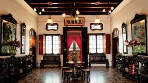 Una habitación tradicional con muebles ornamentados, piso estampado y una mesa central con sillas.