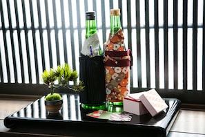 Una bandeja con dos botellas, una pequeña planta en maceta y cartas.