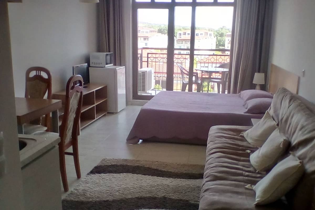 A bedroom with a bed, a sofa, a desk, and a chair.